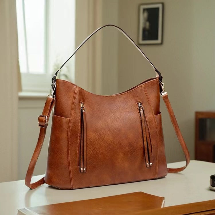 Brown leather handbag on a table with a neutral background