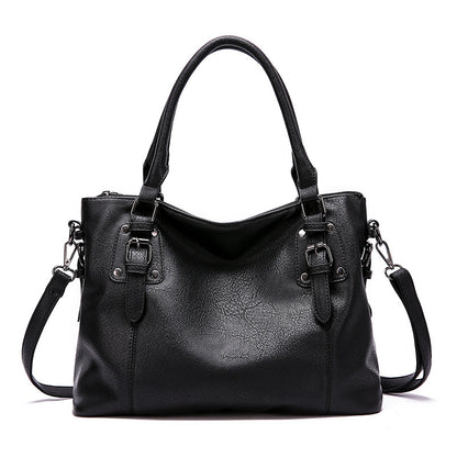 Black leather handbag with shoulder strap on a white background