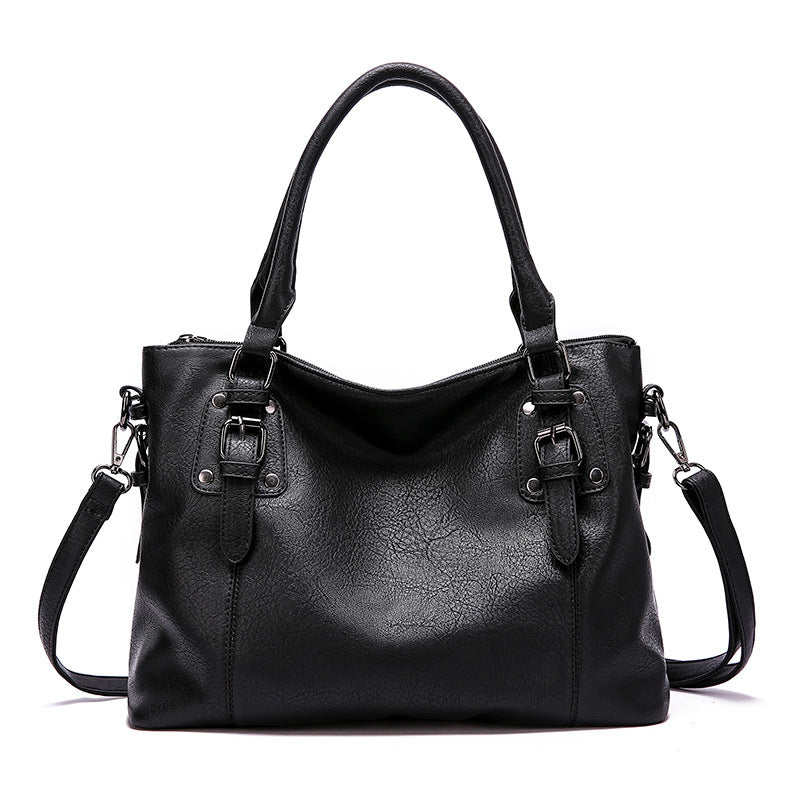 Black leather handbag with shoulder strap on a white background