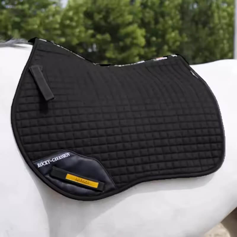 Black quilted saddle pad on a horse with a blurred green background
