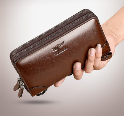 Brown leather wallet held by a hand on a light gray background