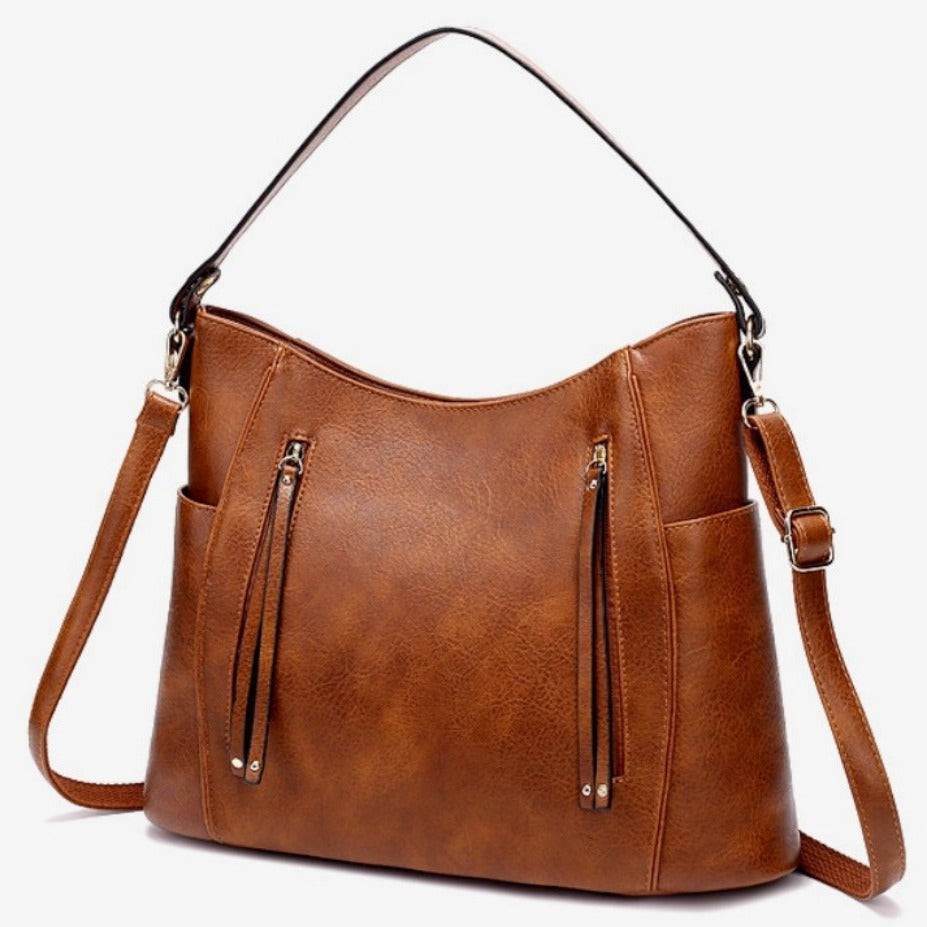 Brown leather handbag with a shoulder strap on a white background
