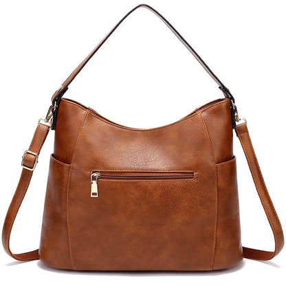Brown leather handbag with a shoulder strap on a white background