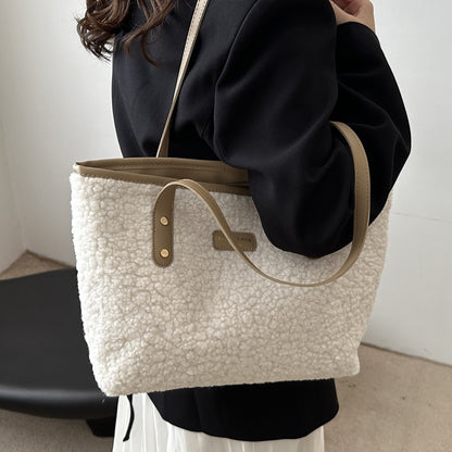 Person holding a textured white tote bag with a brown strap against a neutral background