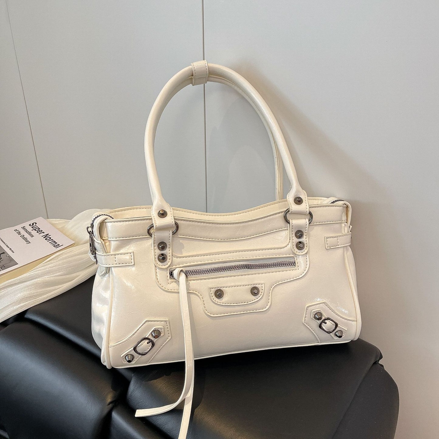 White handbag on a black surface with a light gray background