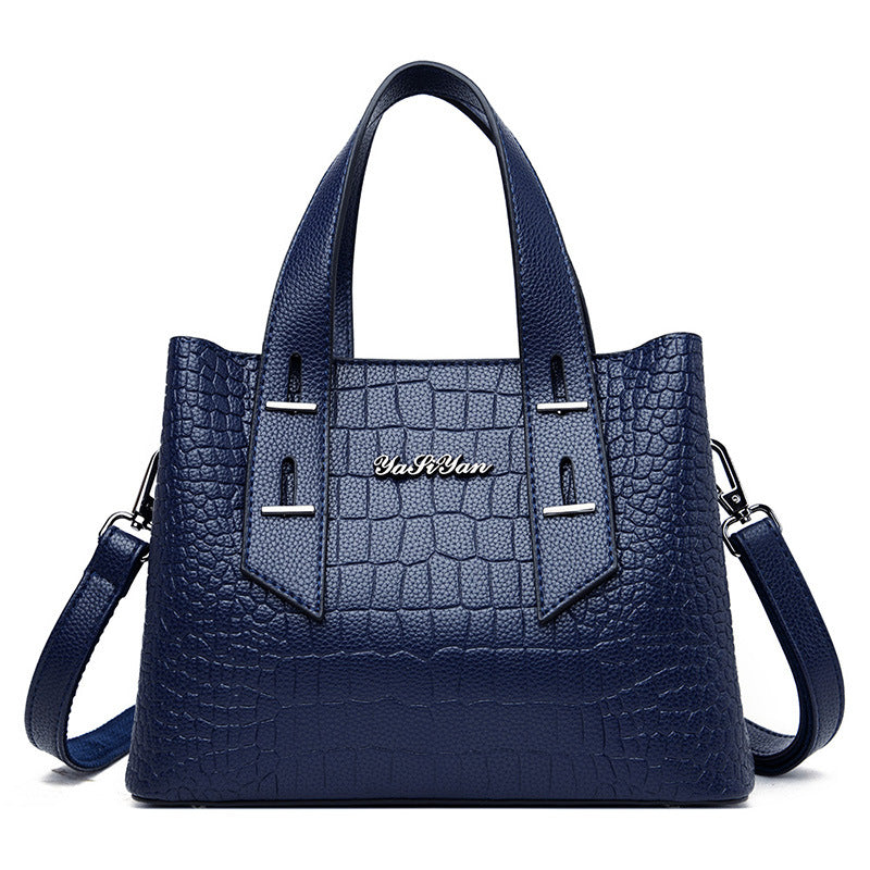 Blue handbag with crocodile texture and visible brand name on a white background