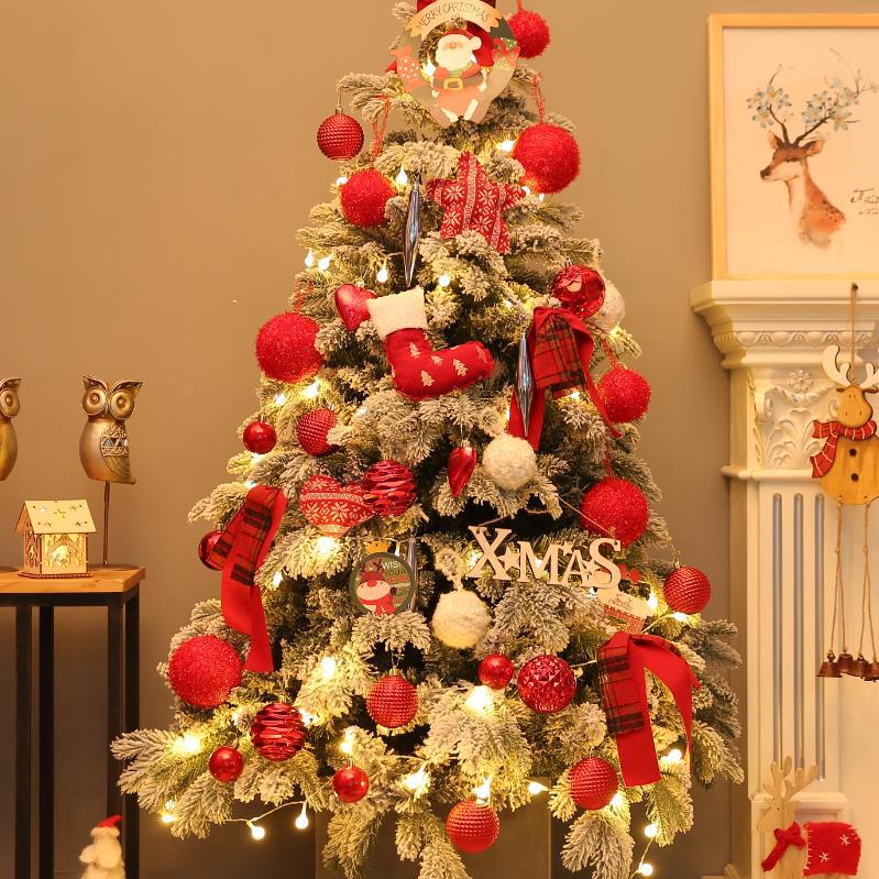 Decorated Christmas tree with red ornaments and lights in a room setting.