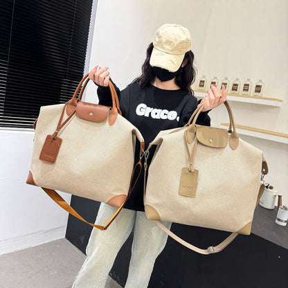 Person holding two beige handbags with brown handles and straps, wearing a black shirt with 'Grace' text.